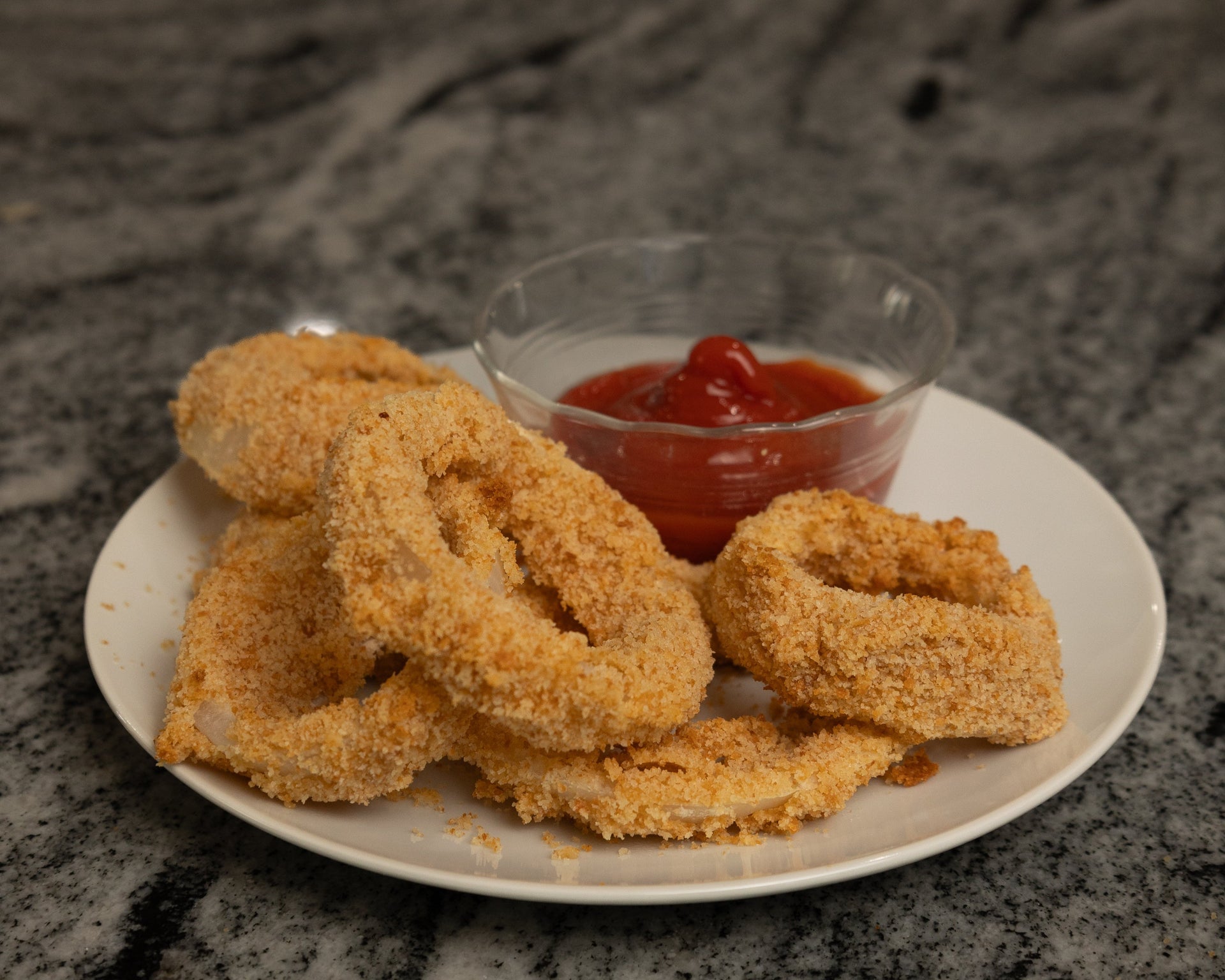 Katz Gluten Free onion rings on a plate with ketchup dip.